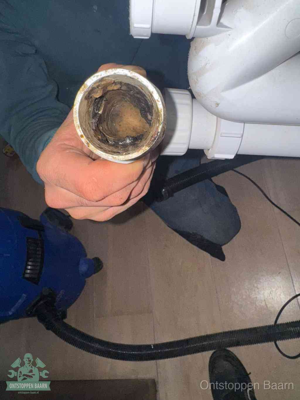 Een losgekoppeld PVC-afvoerbuisstuk dat van binnen volledig is dichtgeslibd met vet en vuil, de meest voorkomende oorzaak van verstoppingen in Baarn