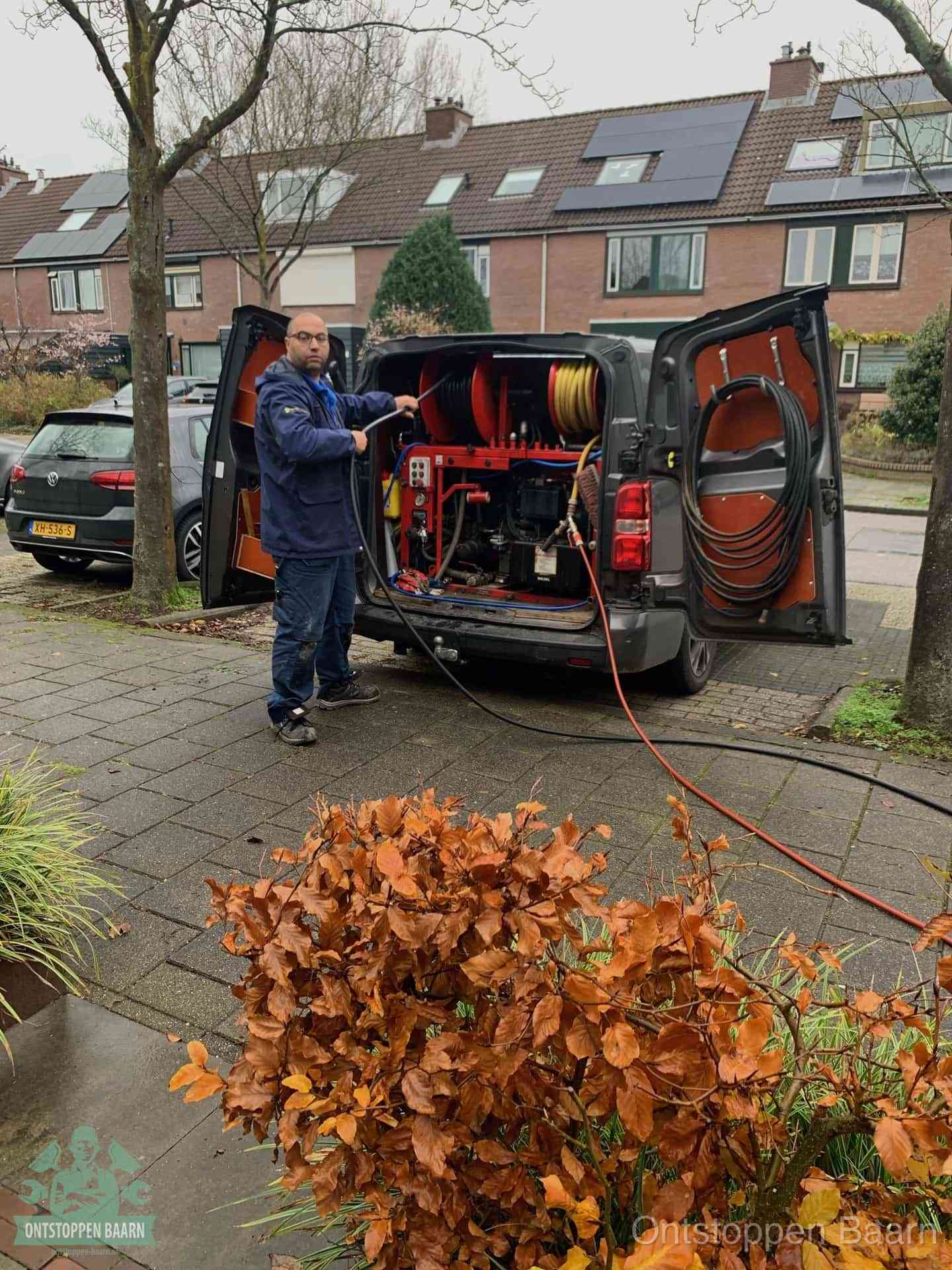 Een monteur staat bij zijn open bestelbus met hogedruk-rioolreinigingsapparatuur, klaar om binnen 30 minuten uit te rukken voor een spoedverstopping in Baarn