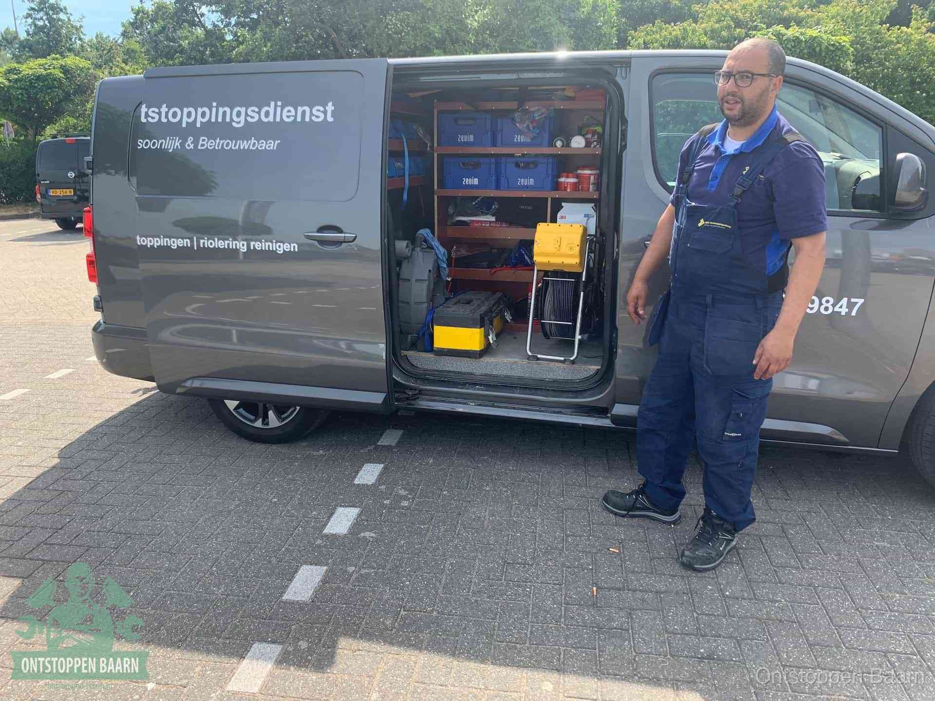 Een monteur staat klaar bij zijn bedrijfsbus met gereedschap, de vaste werkwijze van de ontstoppingsdienst in Baarn